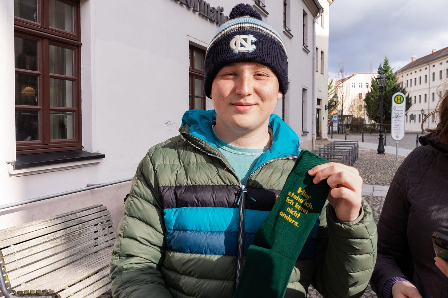 The author, in a North Carolina toboggan and green puffer jacket, holds a pair of green socks that translates to, "here I stand, I can do no other." The author is a Lutheran, he spent time in Germany on a Luther tour, the socks were a must.