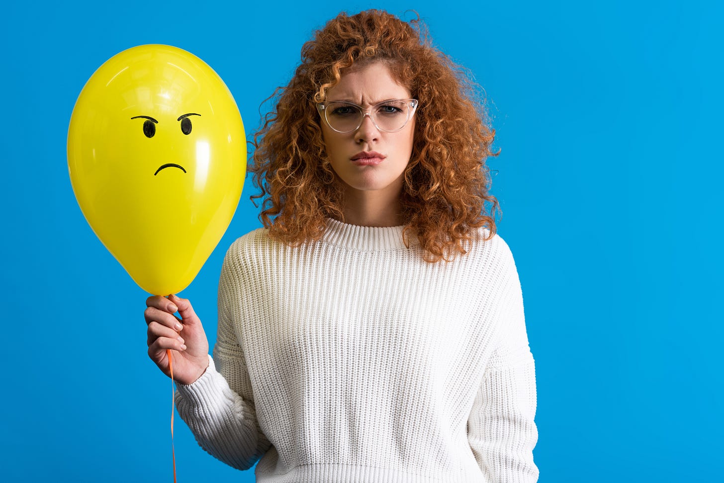 Angry woman holding a balloon with angry face.