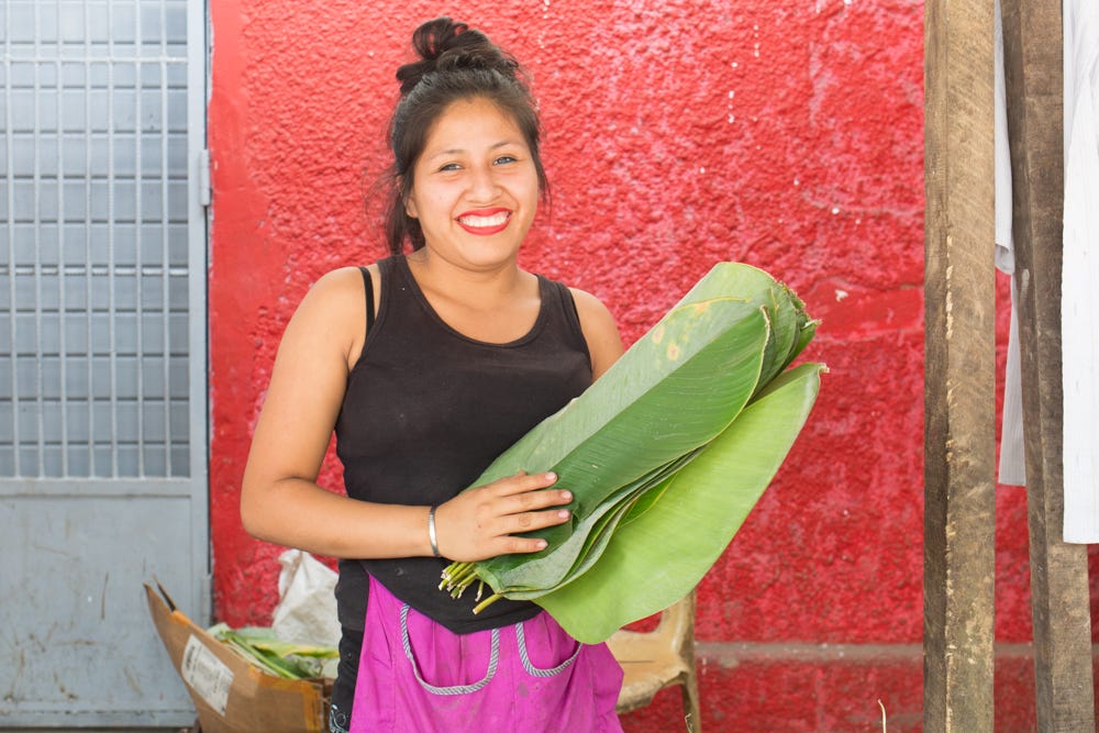 Market vendor showing off large bijao leaves