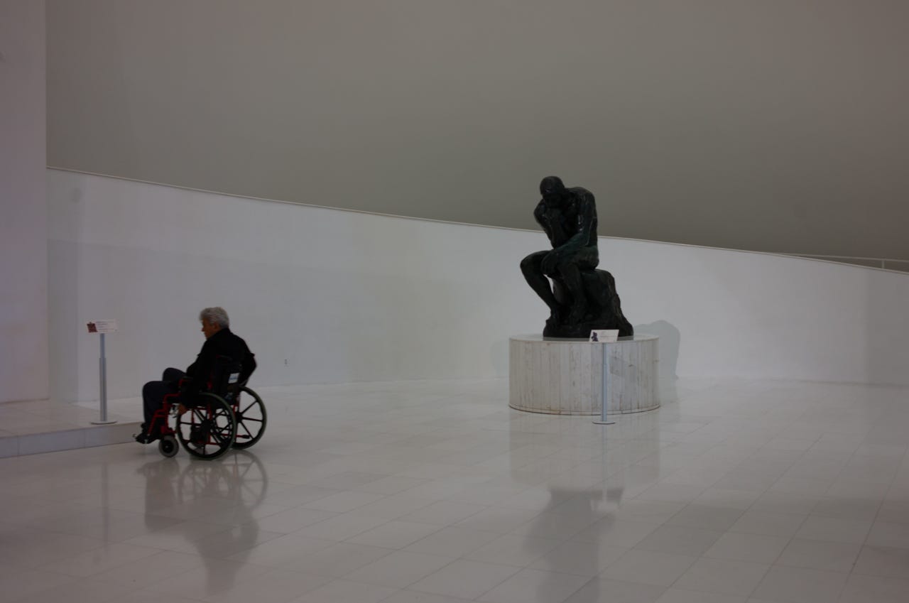 A person in a wheelchair and a statue

Description automatically generated