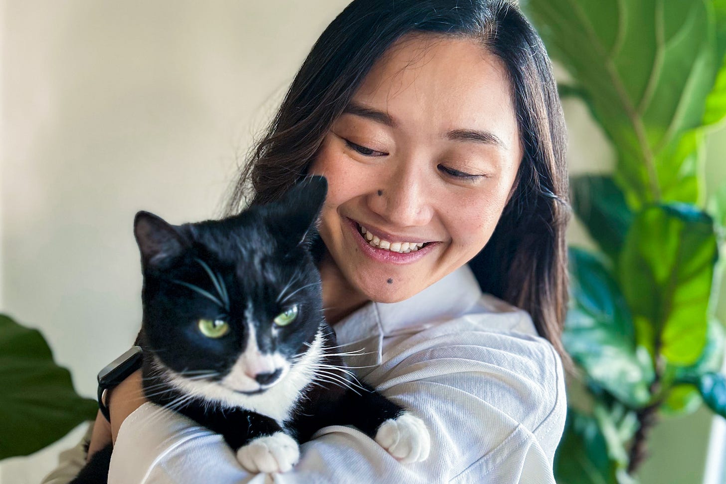 Woman with long brown hair holding a cat smiling