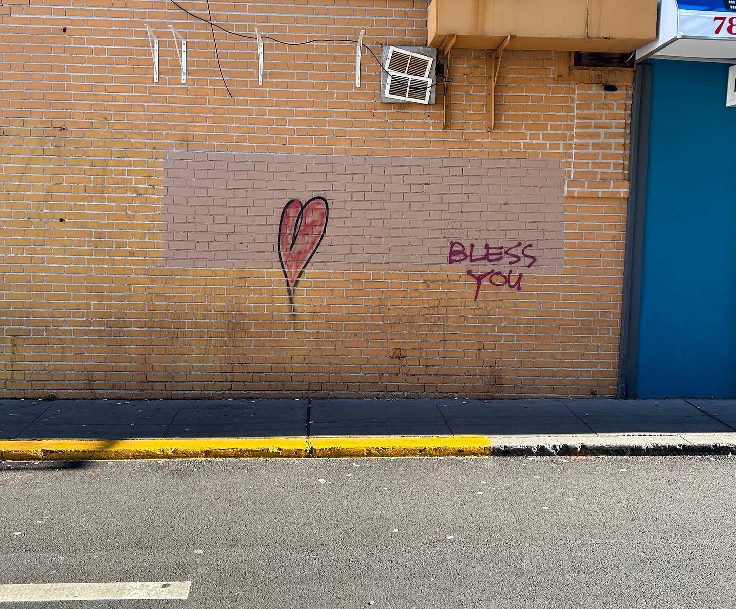 Graffiti on the side of a building -- a heart, and the words "bless you"