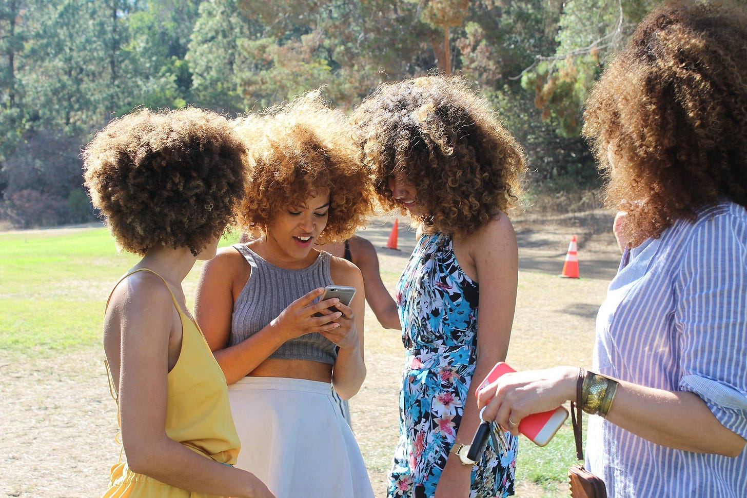 Photo of four women talking and looking at a cellphone together