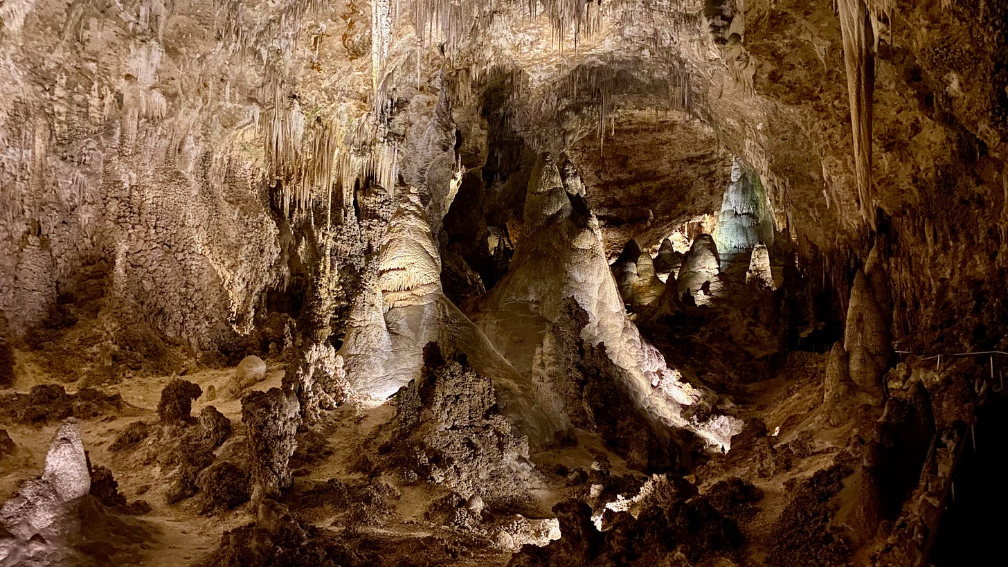 a huge cave room with flow stones, stalactites and stalagmites, lit from below