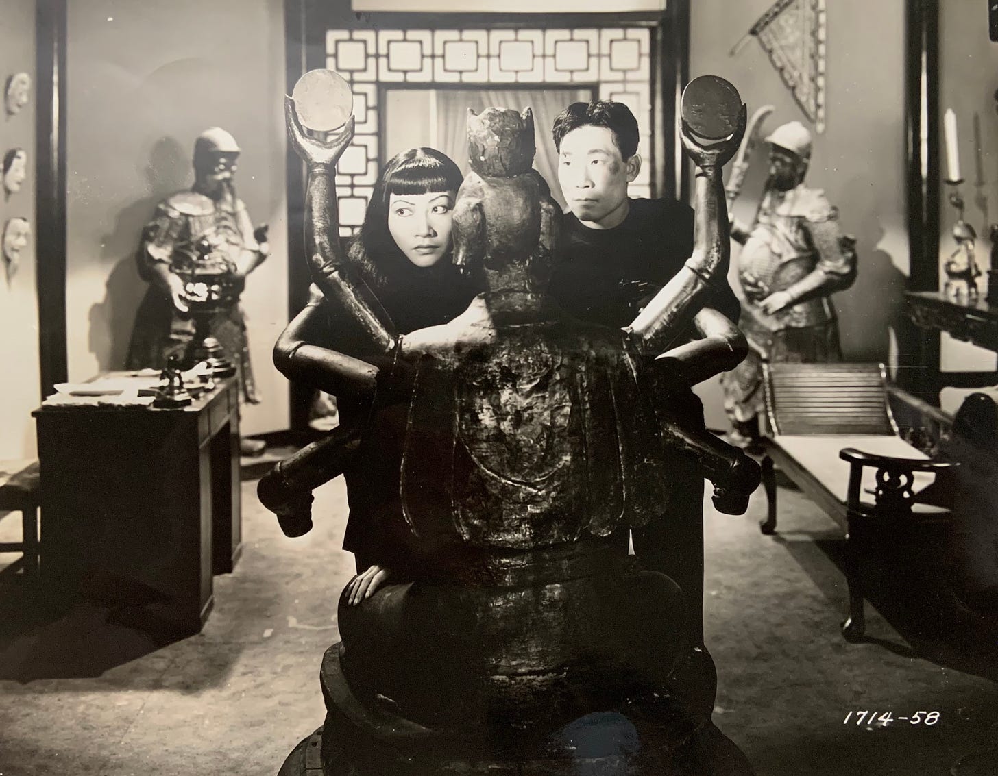 AMW and Philip Ahn hide behind a buddhist statue in a scene from Daughter of Shanghai (1937)