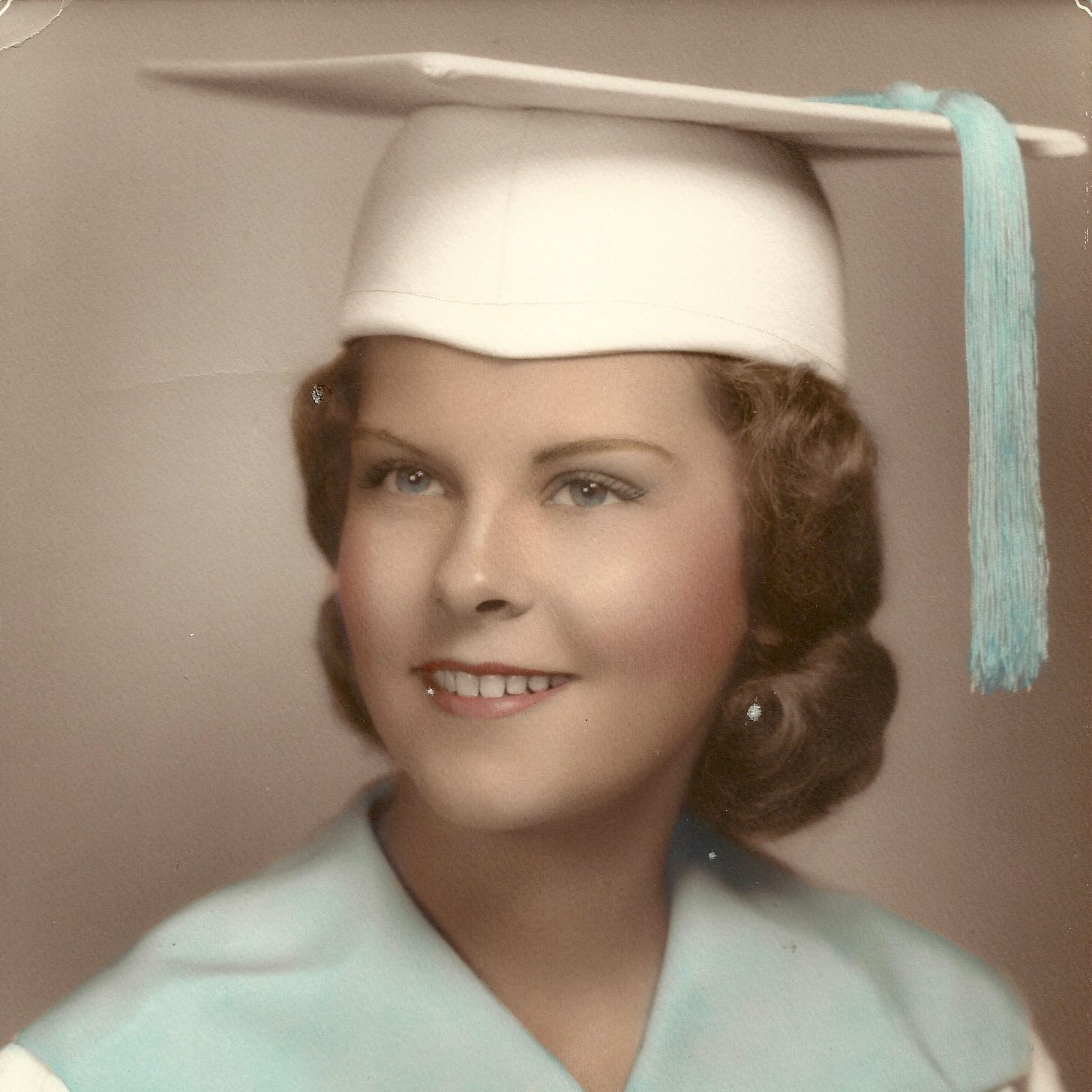 Bright-eyed young woman in a graduation cap, circa 1959