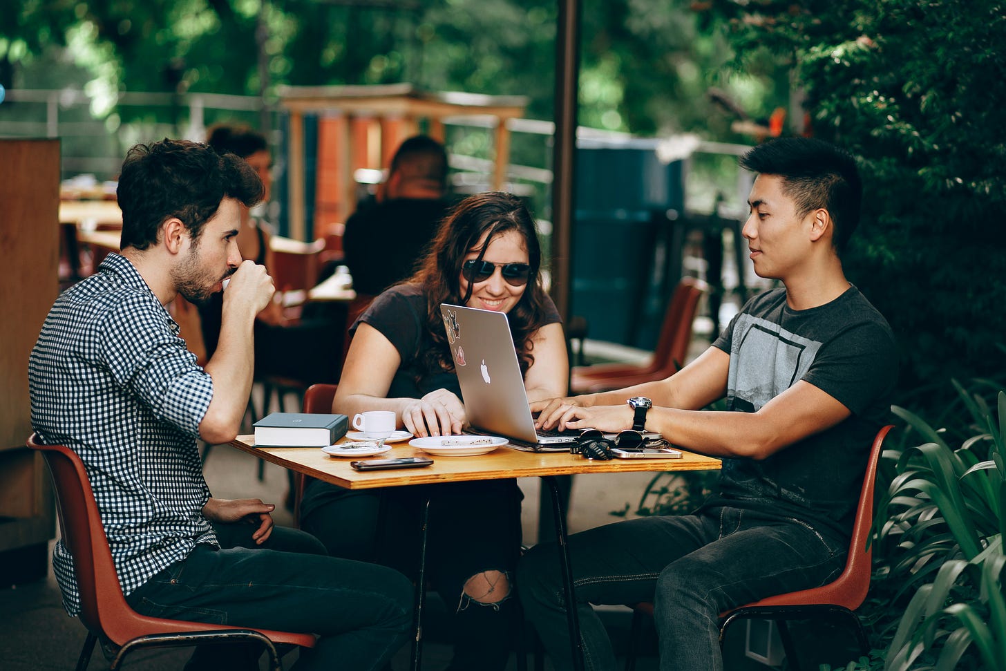 Three young, hip-looking folks getting coffee and chatting.