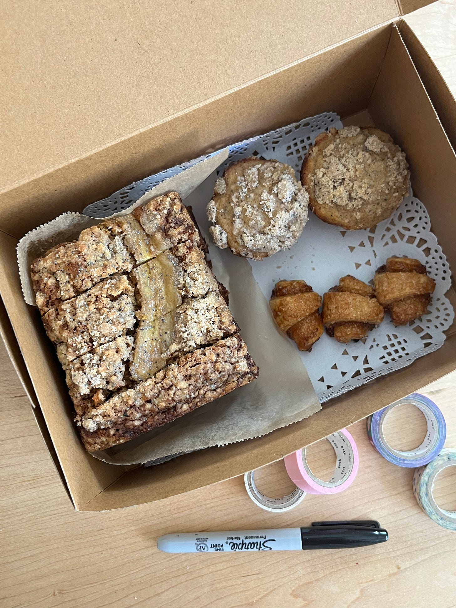 Overhead shot of a kraft box filled with banana bread, muffins, and rugelach.