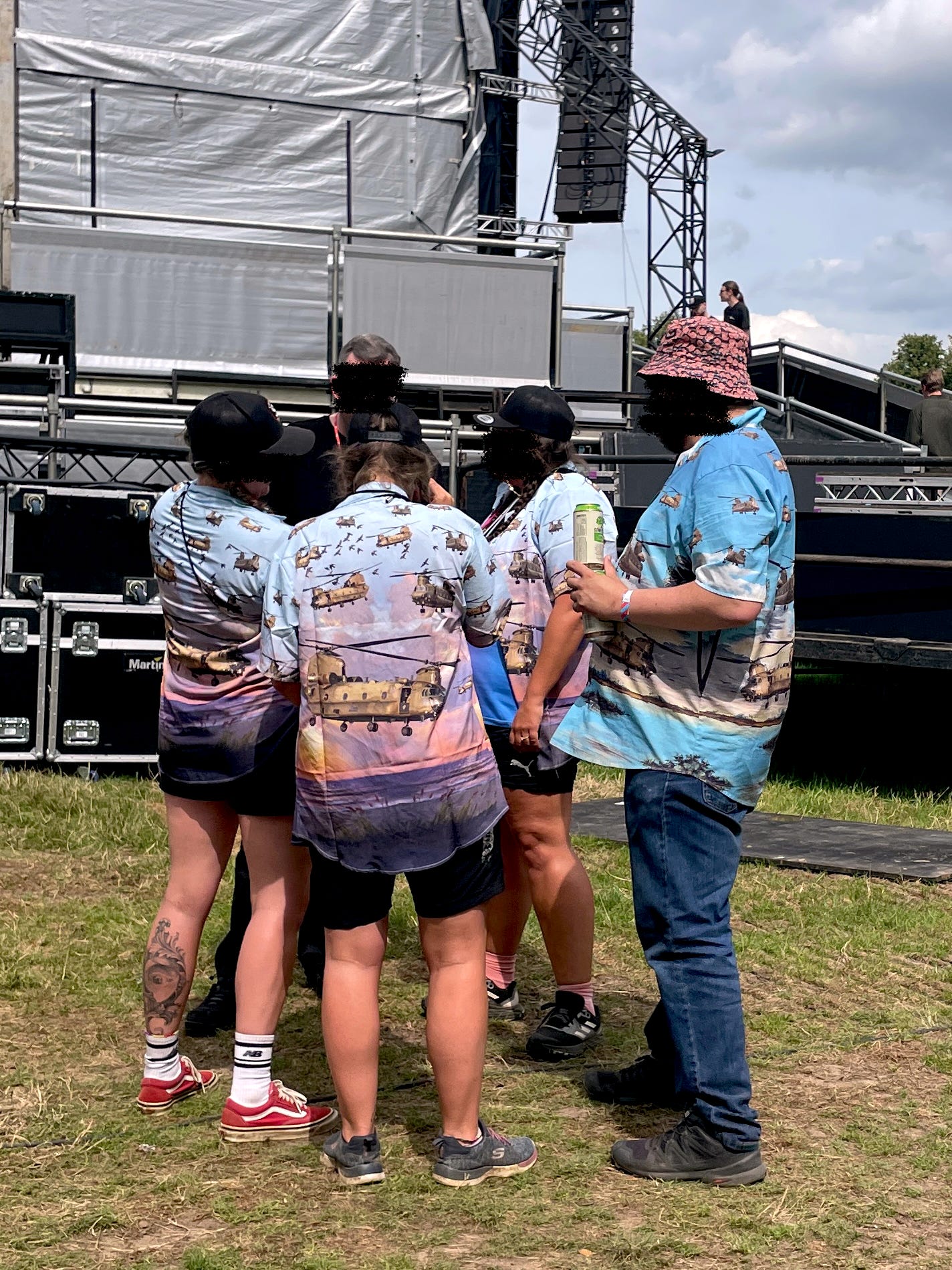 Four festival attendees wear graphic shirts illustrated with British military helicopters.