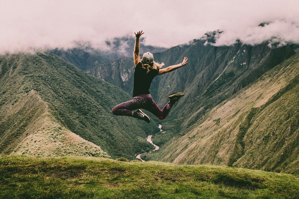 Person leaping in the air. Mountains in the background.