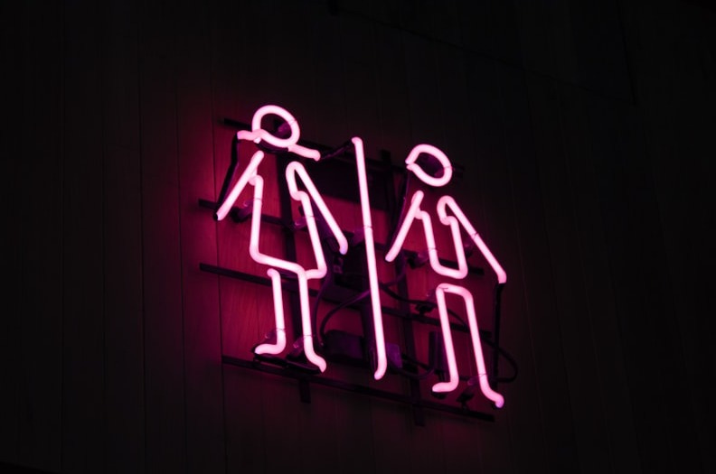 man and woman neon signage at dark area