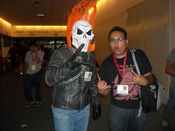 Cosplayer dressed as Ghost Rider and Henry Barajas throwing metal hands with a backpack strap on his left shoulder at San Diego Comic Con 2009.