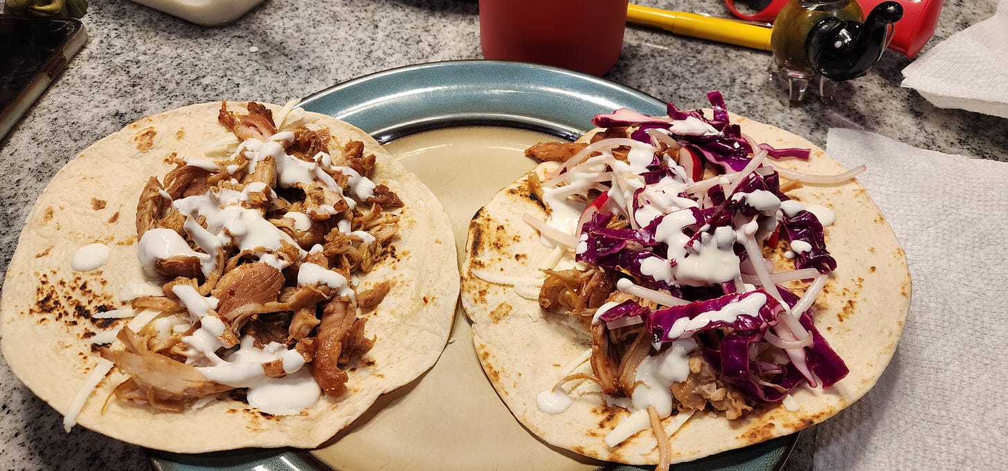 two open chicken bulogi tacos with shredded meat, white sauce, and pickled veg