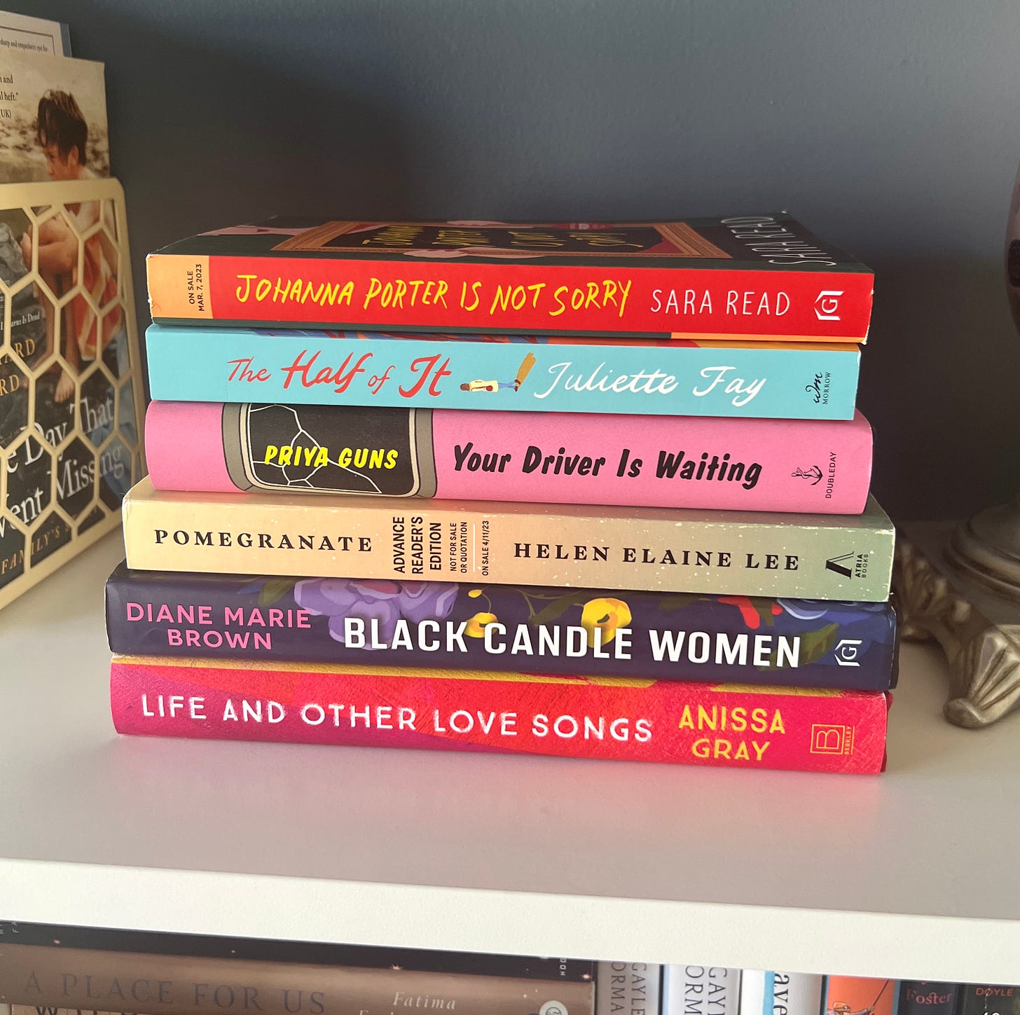 A stack of books featuring Johanna Porter Is Not Sorry, The Half of It, Your Driver Is Waiting, Pomegranate, Black Candle Women, and Life and Other Love Songs