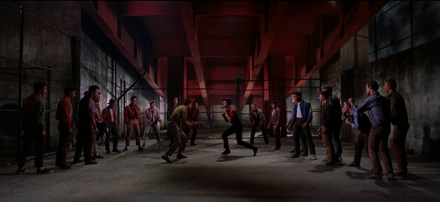 Widescreen still from 1961 film West Side Story. The two gangs - Jets and Sharks - square up under the highway for their rumble