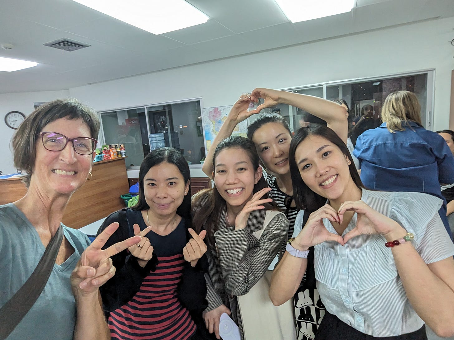 one white woman (me) with four young Thai women, all of us making a cute gesture with our hands