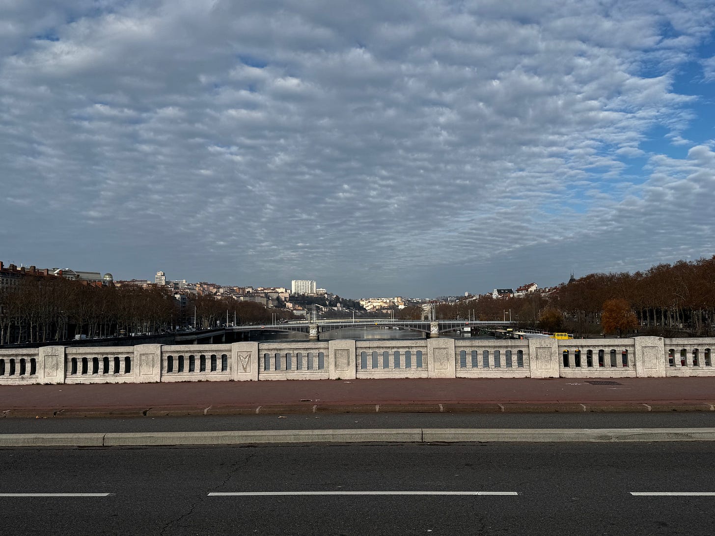 Photo from a bridge crossing the Rhone river of buildings on the hillside of the right bank.
