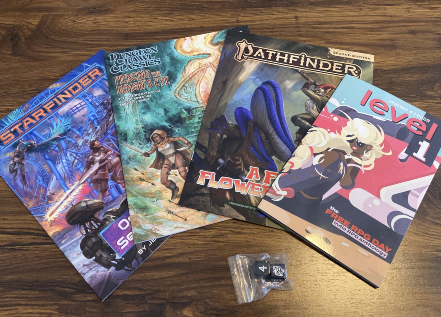 My personal haul, consisting of three adventures, a pair of dice, and an anthology of indie RPGs