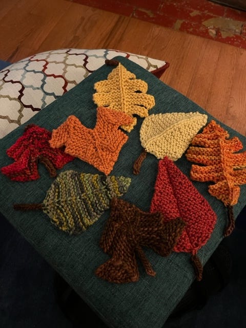 A collection of knitted leaves in green and brown and red and yellow,