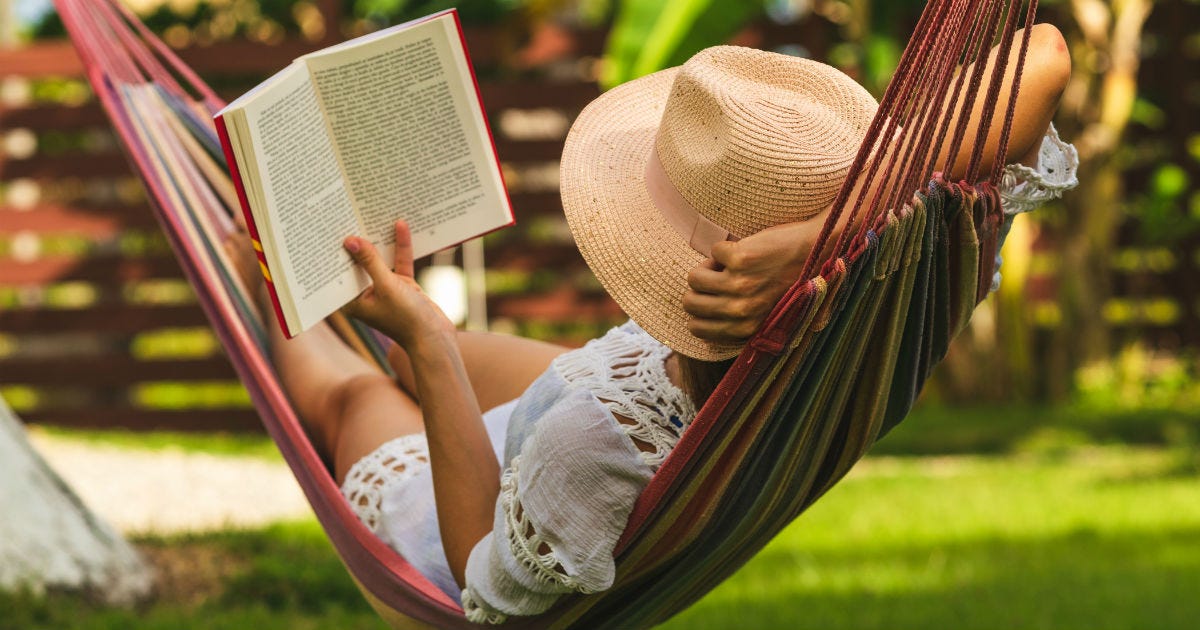 Woman relaxing in a hammock, reading a book on a summer day