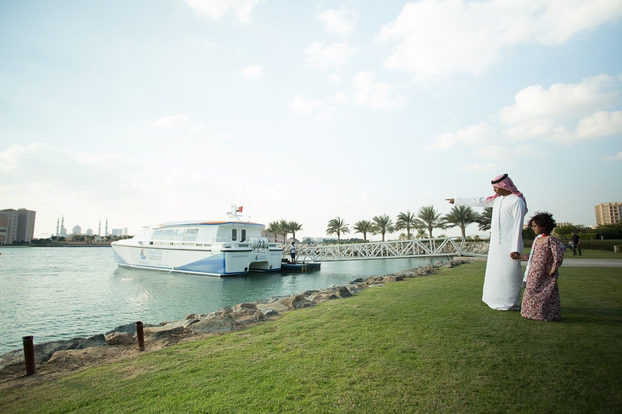 A photo of a man in Middle Eastern dress pointing at a yacht