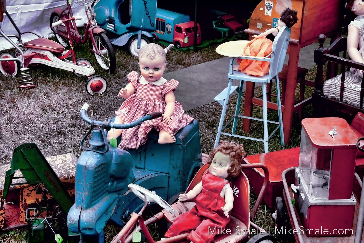 A creepy doll sitting atop a derelict toy scooter.