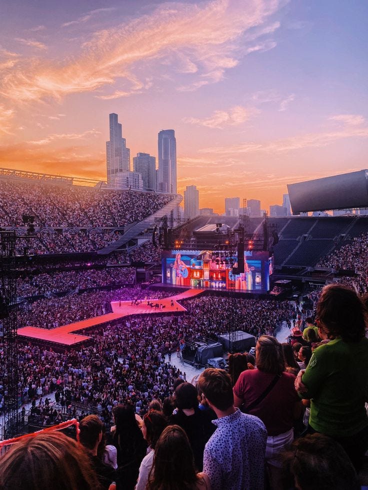 This may contain: a large crowd is watching a concert in the middle of an arena at sunset or sunrise