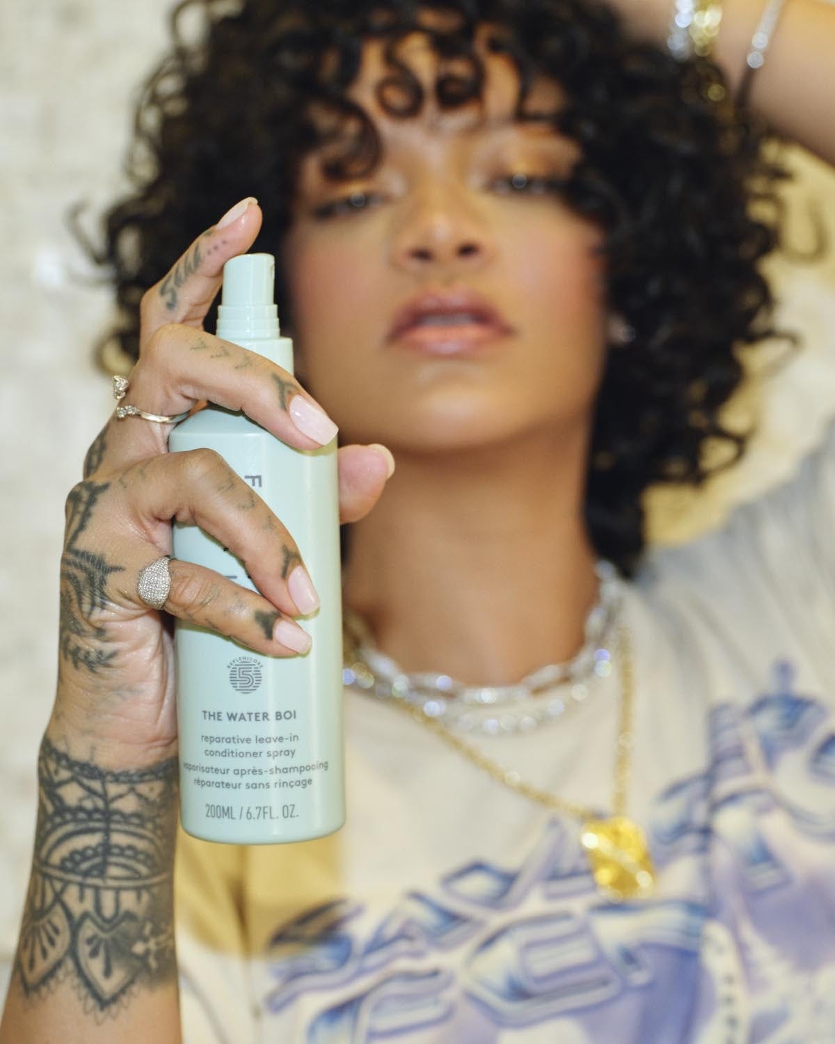 Rihanna holding Water Boi Leave-In conditioner