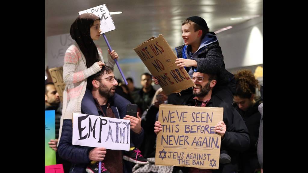 Meryem Yildirim, 7, left, sitting on the shoulders of her father, Fatih, of Schaumburg, and Adin Bendat-Appell, 9, sitting on the shoulders of his father, Rabbi Jordan Bendat-Appell, of Deerfield, protest President Donald Trump's immigration and refugee order at O'Hare International Airport on Jan 30, 2017.