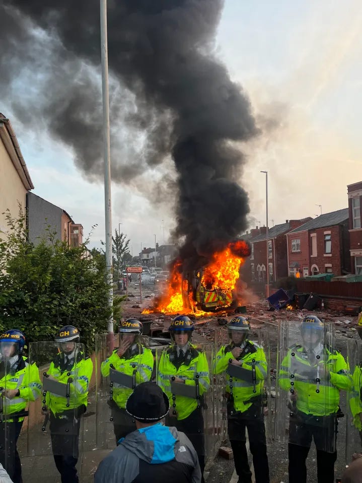 Southport police stand as a van burns