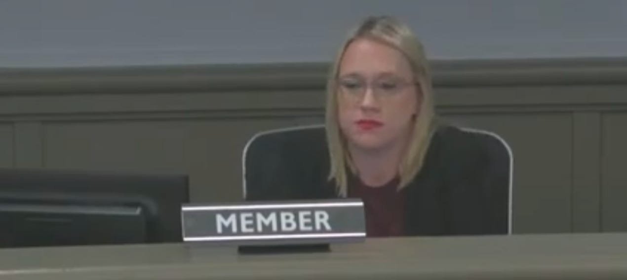 Board Member Heather Rooks, sitting at the dais, looking uncomfortable