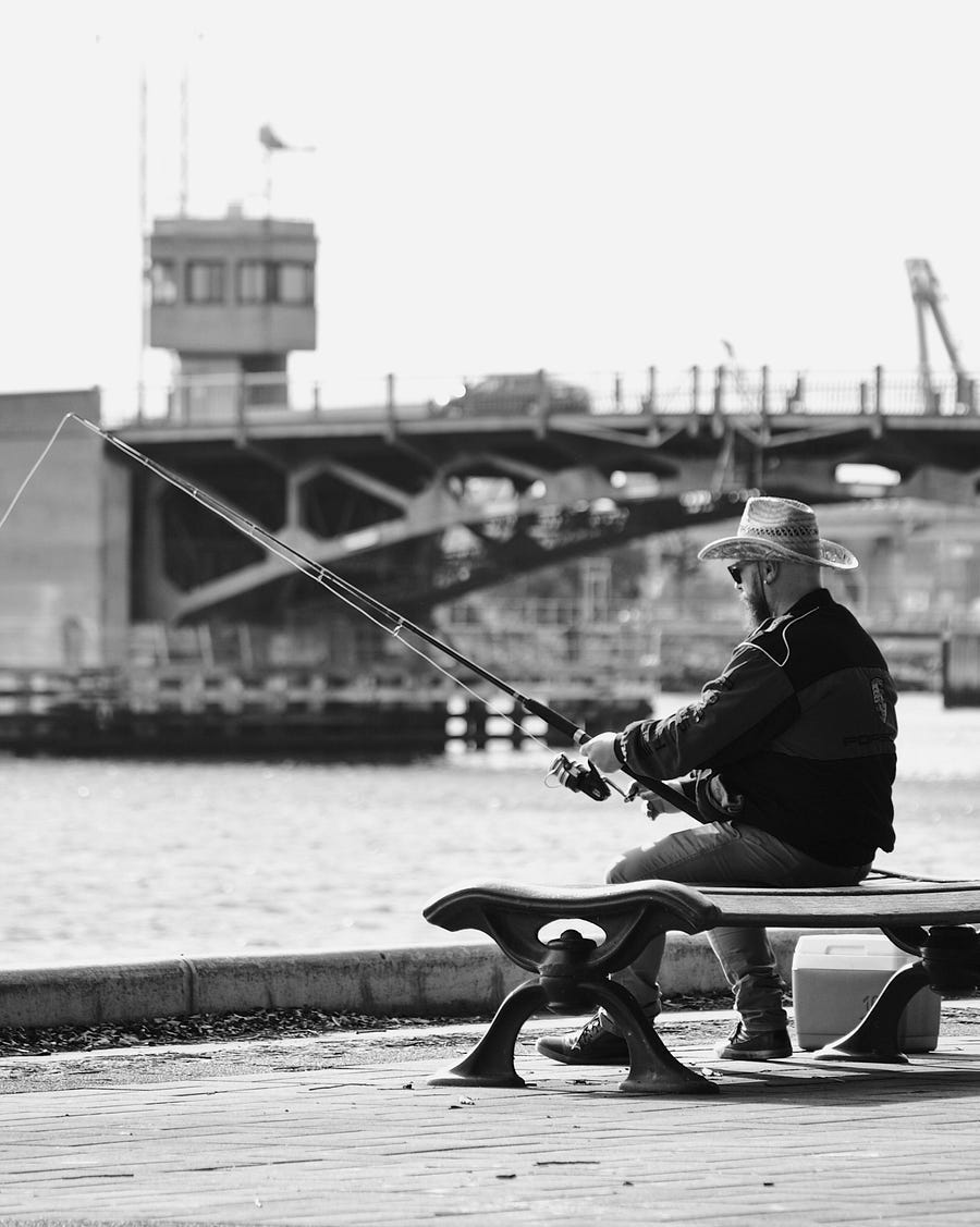 Man with cap and sunglasses fishing.