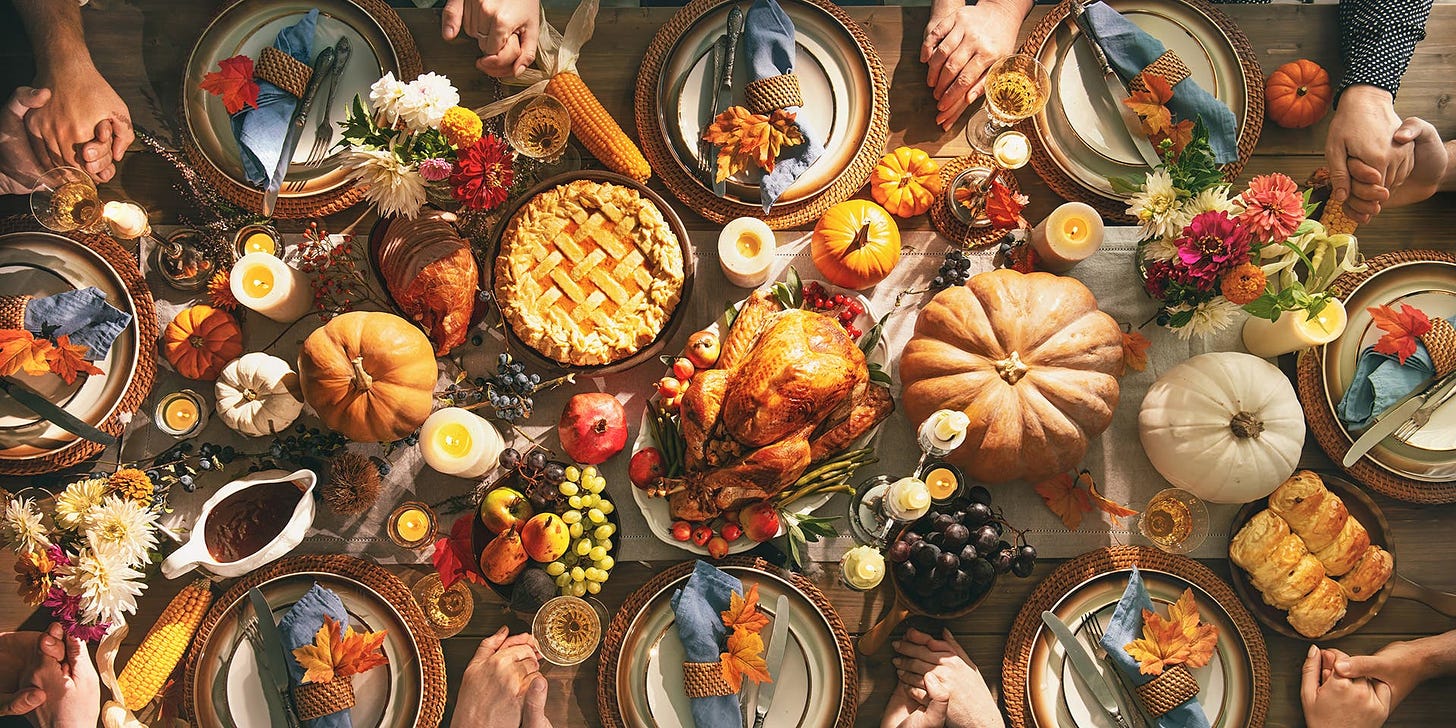 A group of friends or family members hold hands around a Thanksgiving