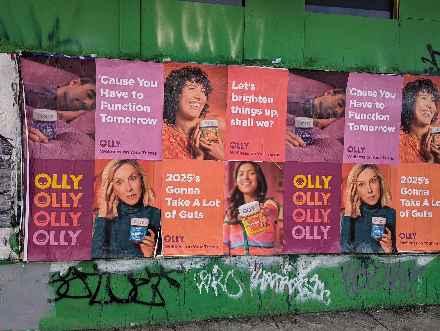 Wall of multicolored posters advertising OLLY supplements, "wellness on your terms"