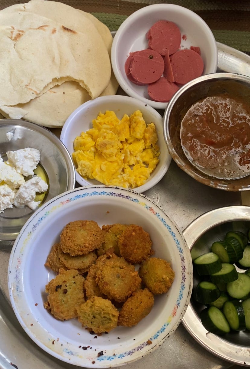 Various small dishes containing eggs, beans, cheese, cucumbers, falafel and flat bread