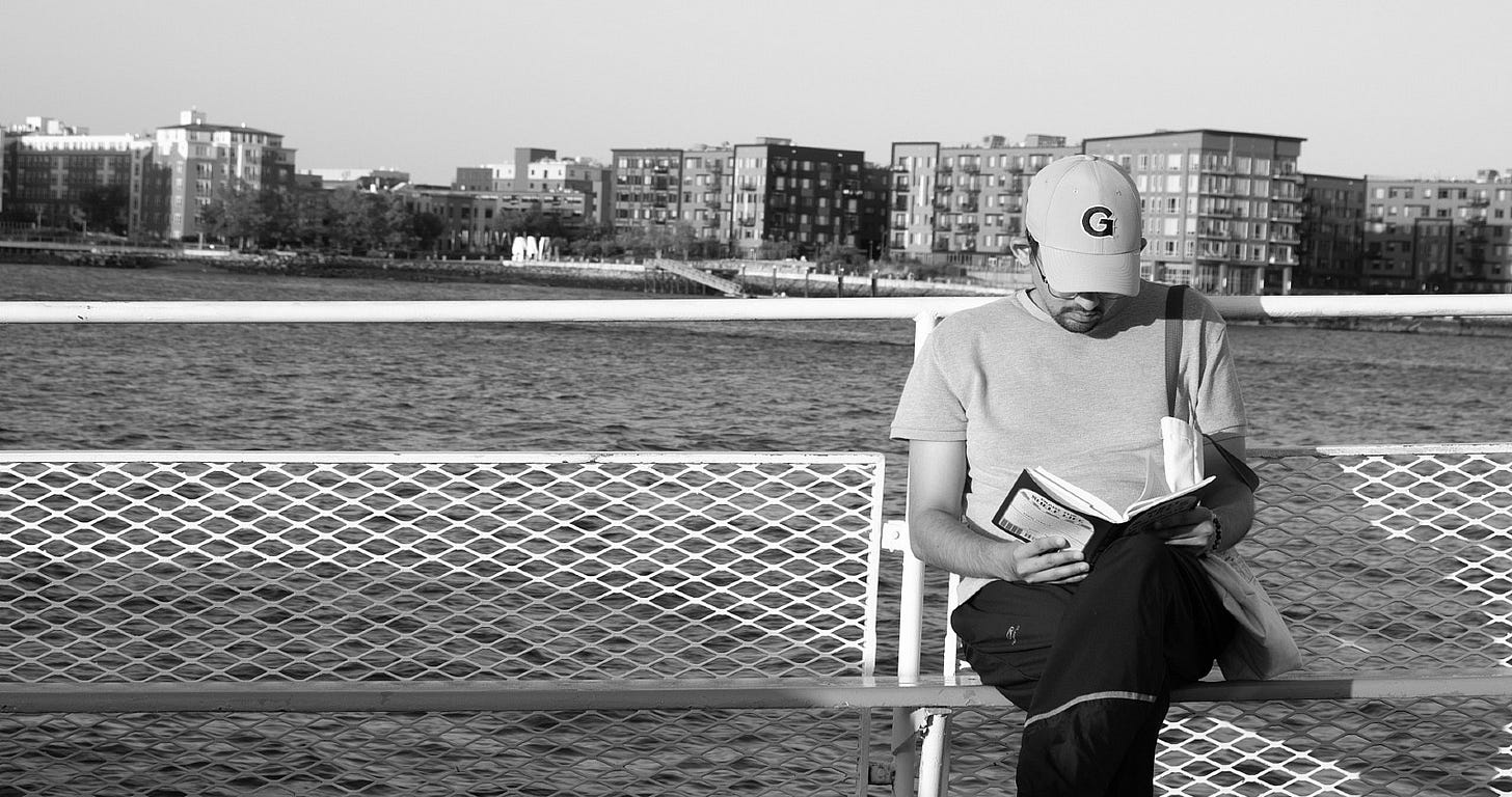 young man reading a book on a bench young man reading a book on a bench