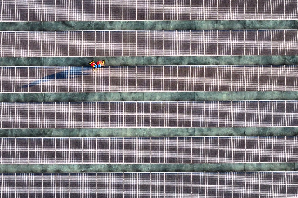 This photo taken on February 21, 2024 shows workers inspecting solar panels at a rooftop of a power plant in Fuzhou, in southern China's Fujian province. 