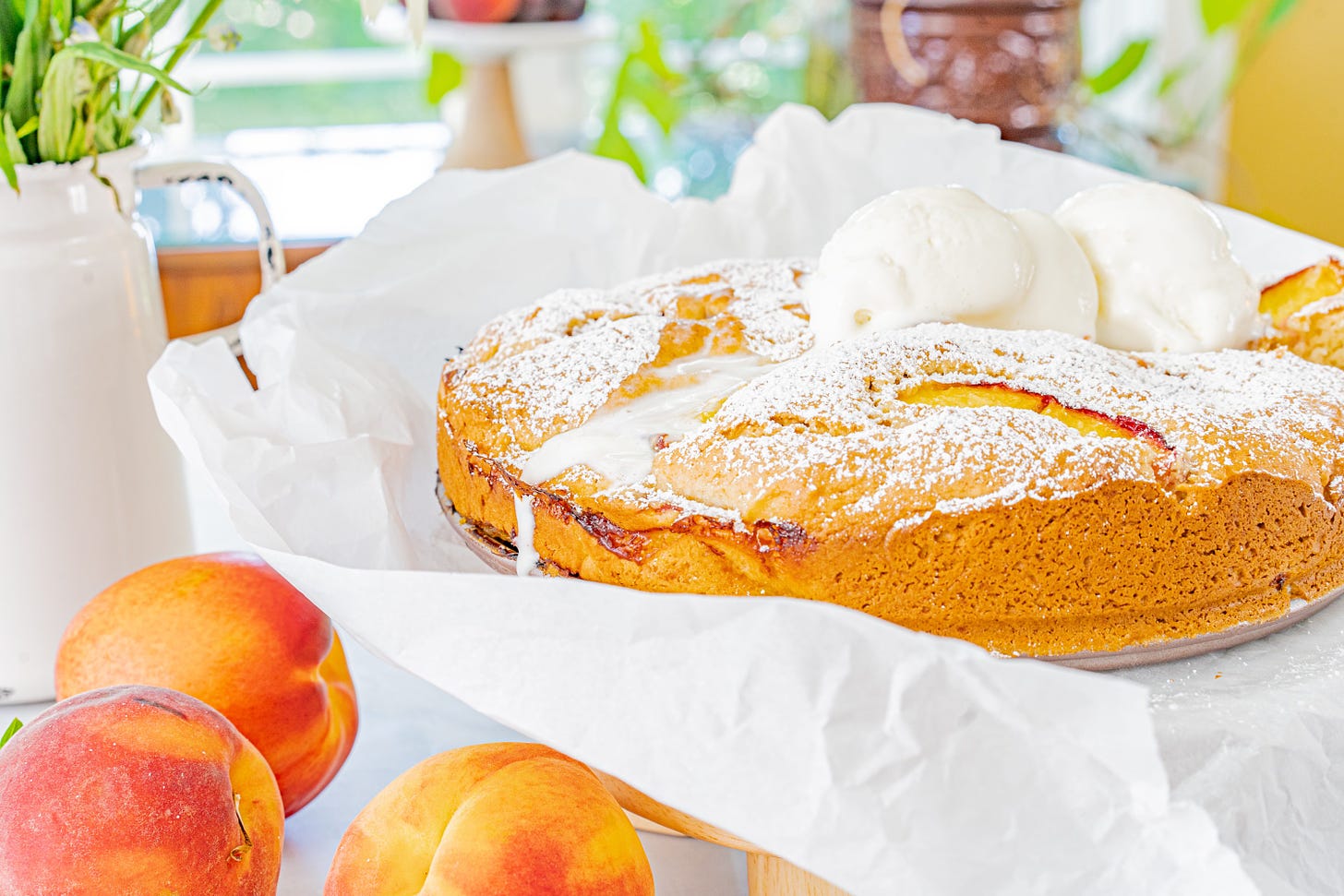 Peach Buckle dessert on white paper with peaches on the side.