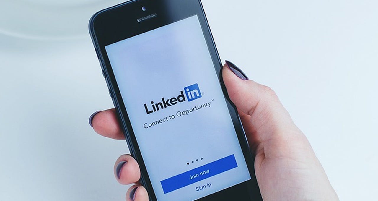 Person holding a smartphone showing the linkedin website