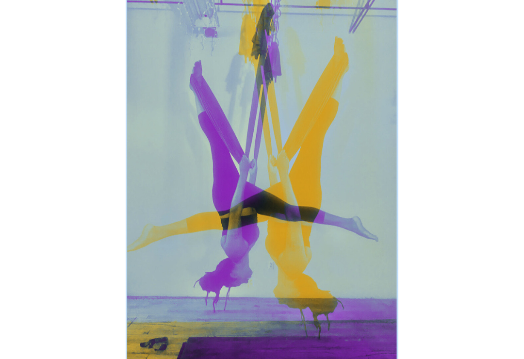 n3vlynnn performs a split on aerial silks, stylized in purple and orange colors