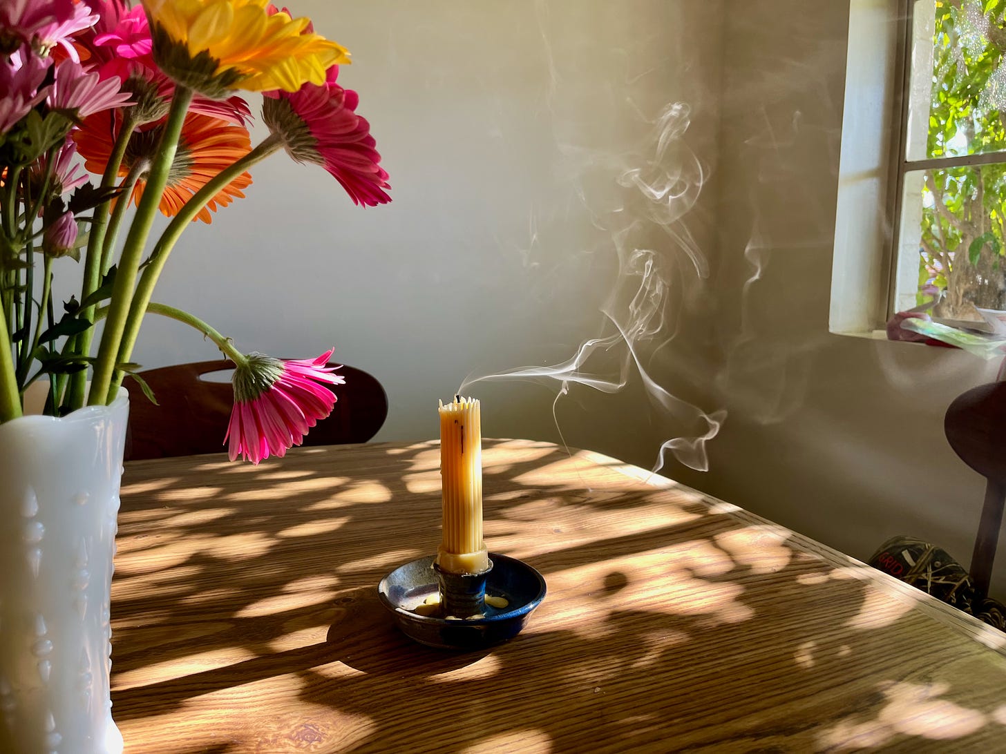 my kitchen table with a vase of flowers and a candle that's just been blown out