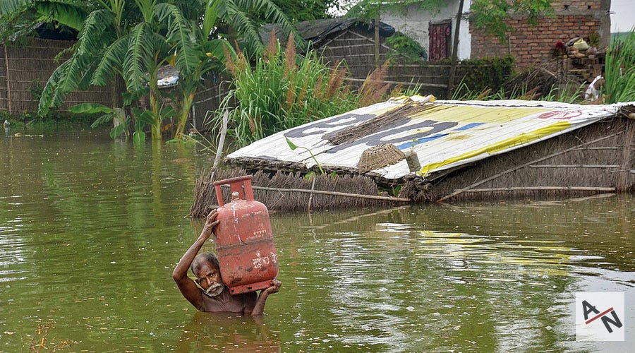 Carrying a gas cylinder, a resident wades through a flooded neighbourhood in Muzaffarpur district, Bihar on Sunday.