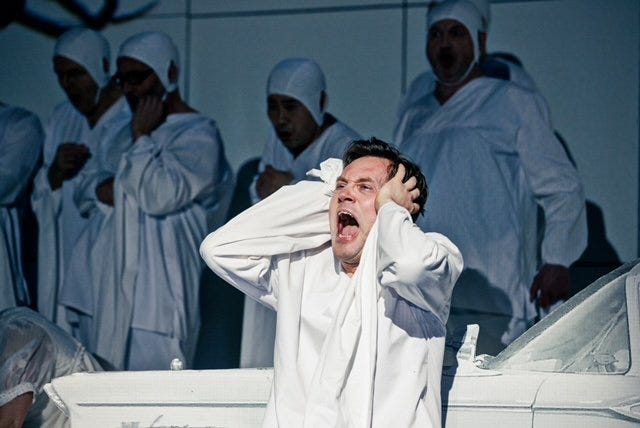 A person in white robe holding his ears

Description automatically generated
