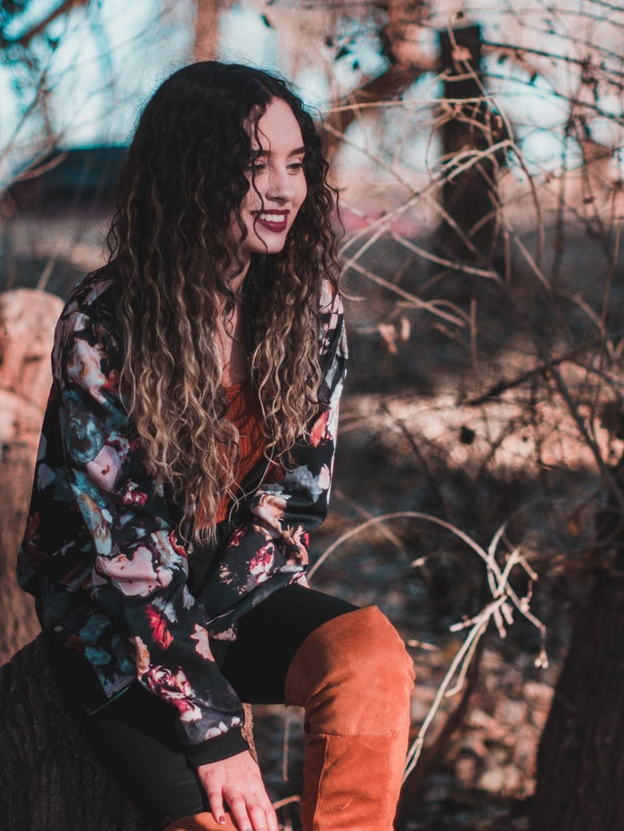 smiling dark-haired young woman sitting in nature