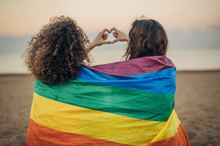 Two women wrapped in a pride flag