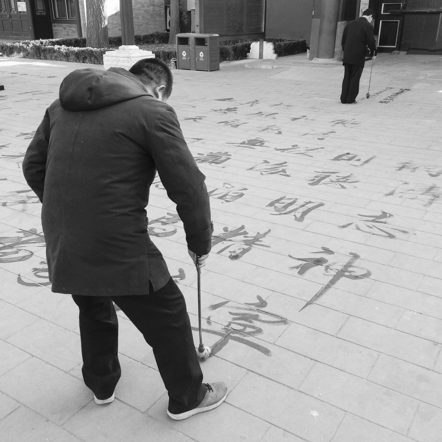 Men practicing water calligraphy in Beijing's Jingshan Park.