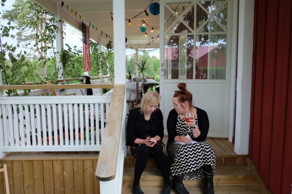 Two women sitting on the steps of a farmhouse in rural Sweden