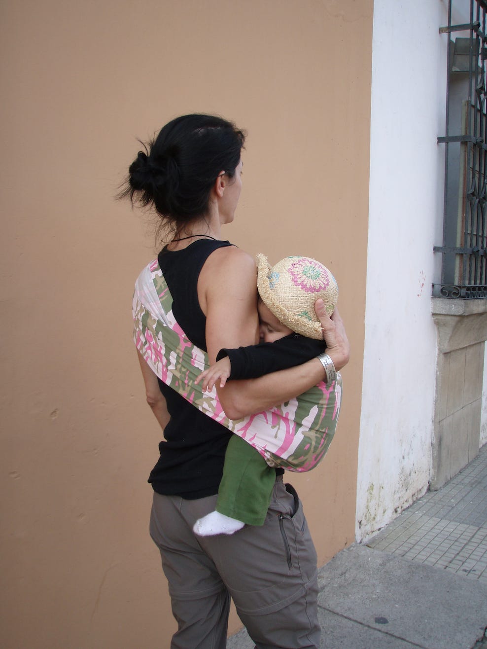 woman walking in guatemala wearing baby in sling