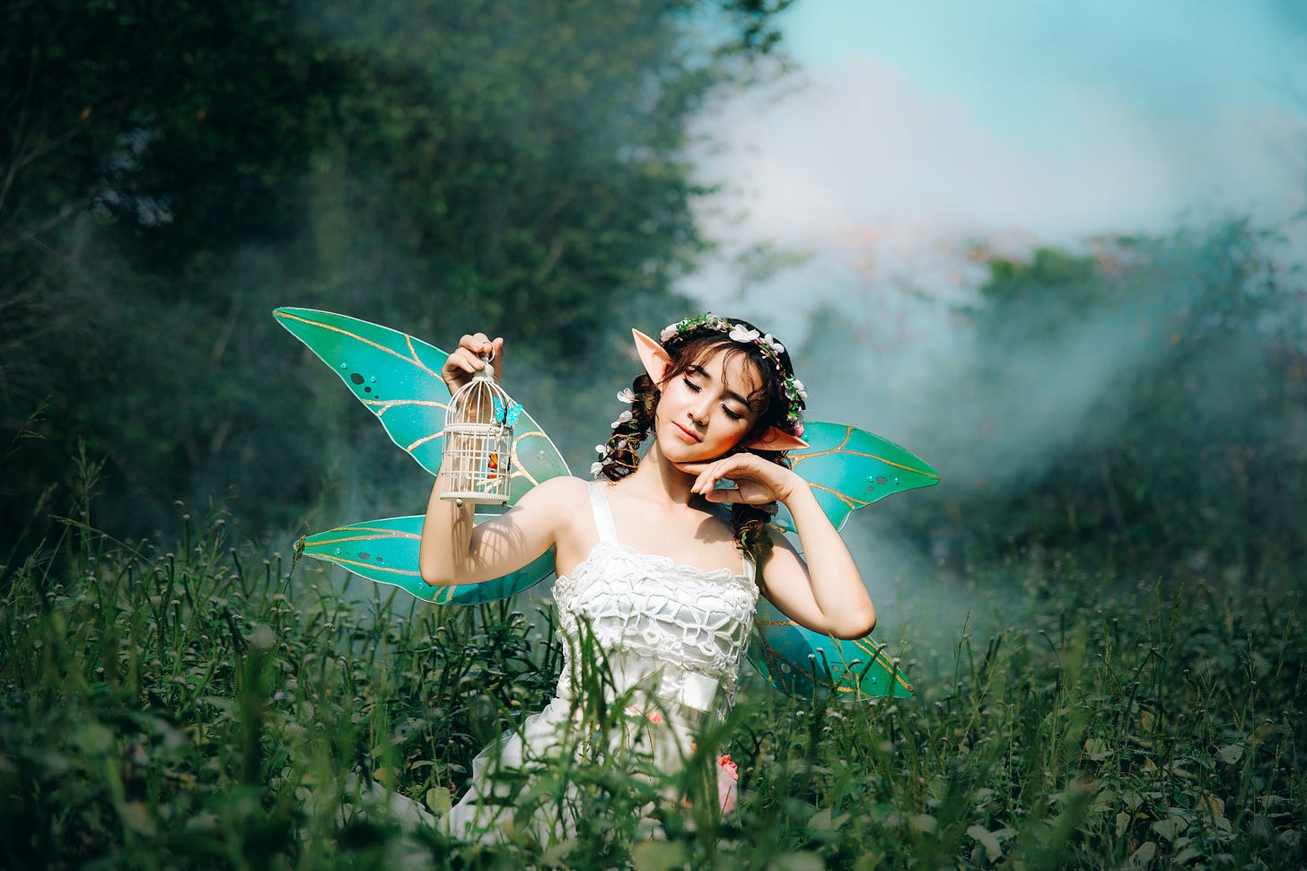 Woman in white dress wearing green fairy wings photo