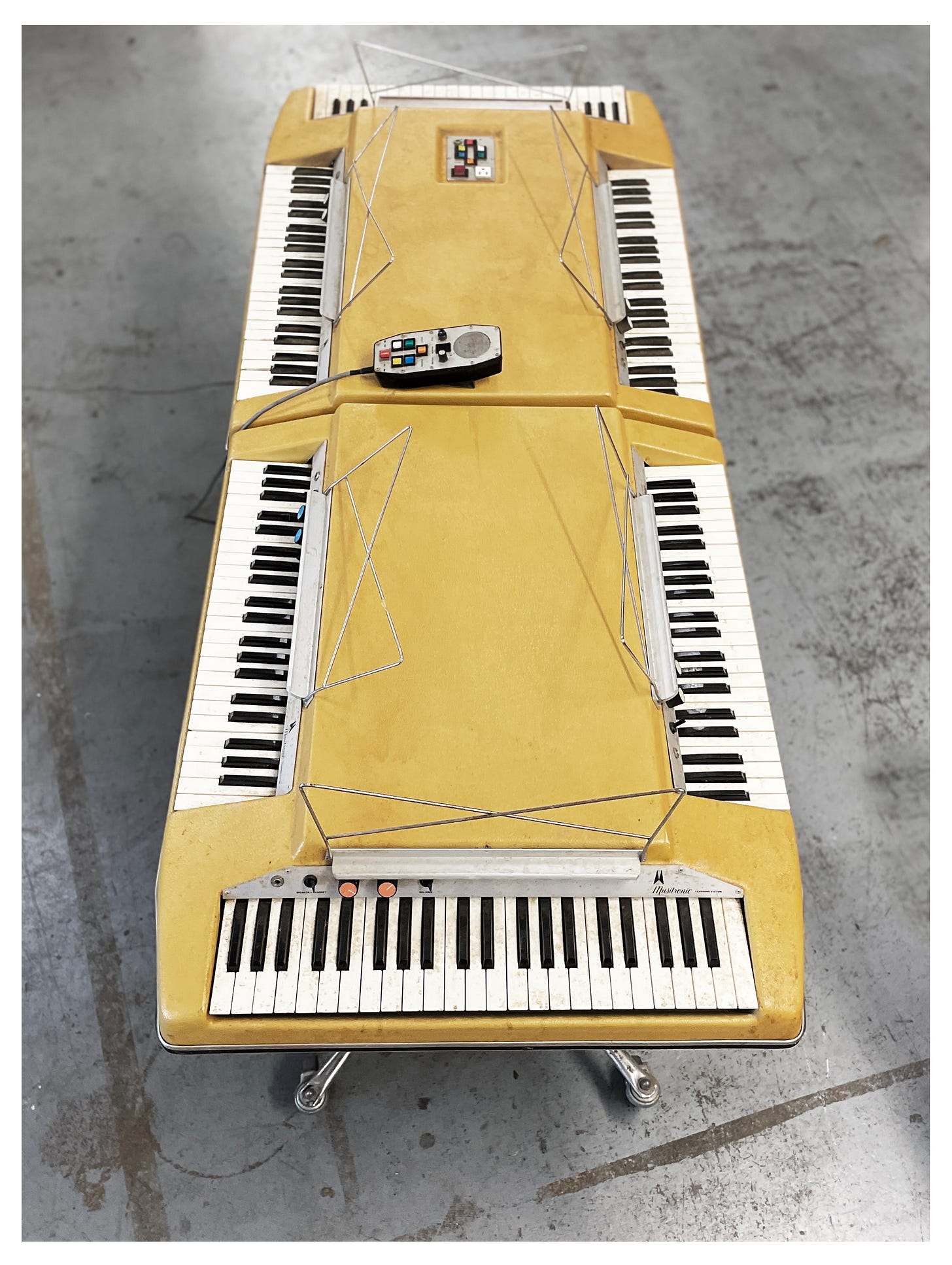 A beige instrument, the Wurlitzer Musitronic Learning System, with six keyboards built into it.